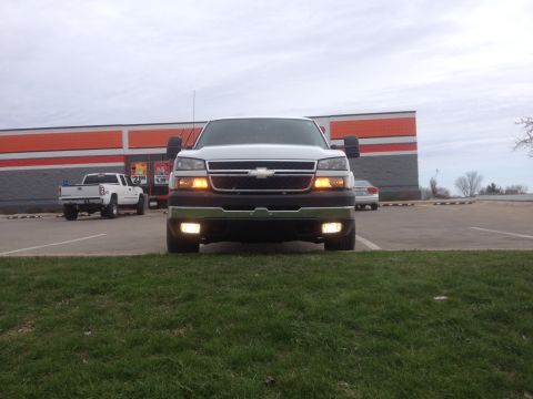 2006 Chevrolet Silverado 2500 - A white 2006 Chevrolet Silverado 2500 pickup truck is parked in front of a building, viewed from the front.