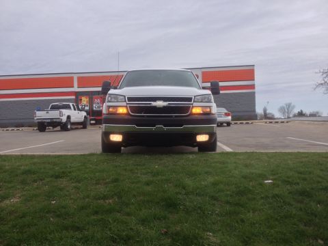 2006 Chevrolet Silverado 2500 - A white pickup truck is parked in front of a store. Another truck is parked to the left.