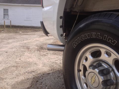 2006 Chevrolet Silverado 2500 - Close-up view of the rear wheel and exhaust of a white pickup truck.
