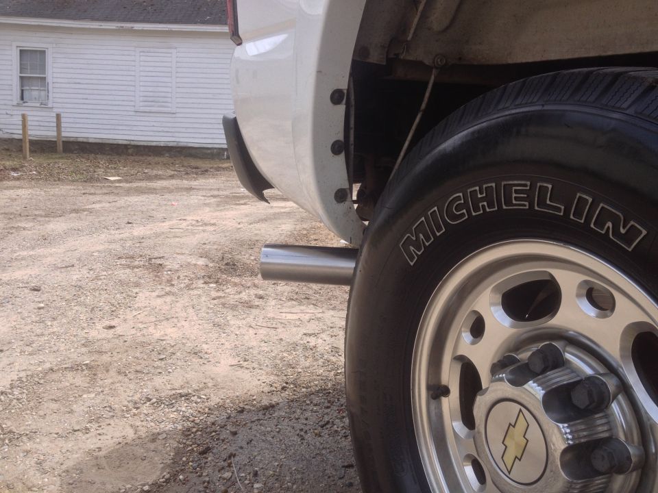 White pickup truck rear quarter panel and tire, with chrome exhaust pipe