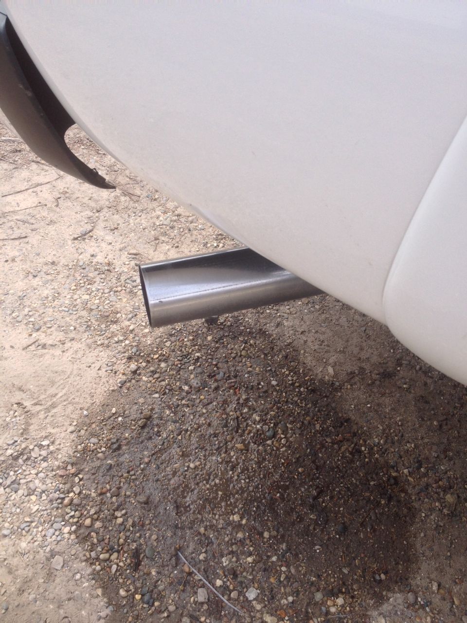 Close-up of a chrome exhaust pipe exiting the rear of a white vehicle