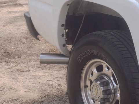 2006 Chevrolet Silverado 2500 - Rear wheel and exhaust pipe detail on a white 2006 Chevrolet Silverado 2500.