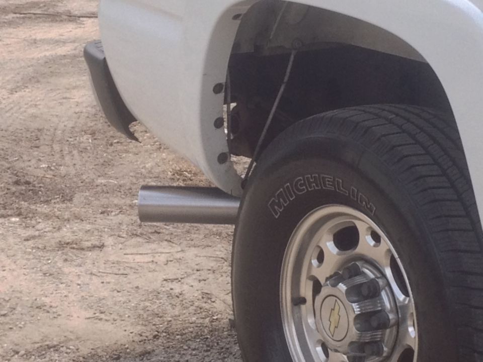 Side view of a white 2006 Chevrolet Silverado 2500's rear wheel and exhaust pipe
