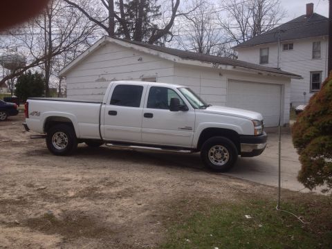 2006 Chevrolet Silverado 2500 - A white 2006 Chevrolet Silverado 2500 pickup truck is parked in a driveway next to a detached garage.