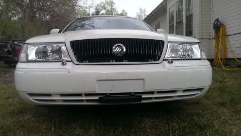 2000 Mercury Grand Marquis - The front of a white Mercury Grand Marquis is shown parked outdoors in front of a house.