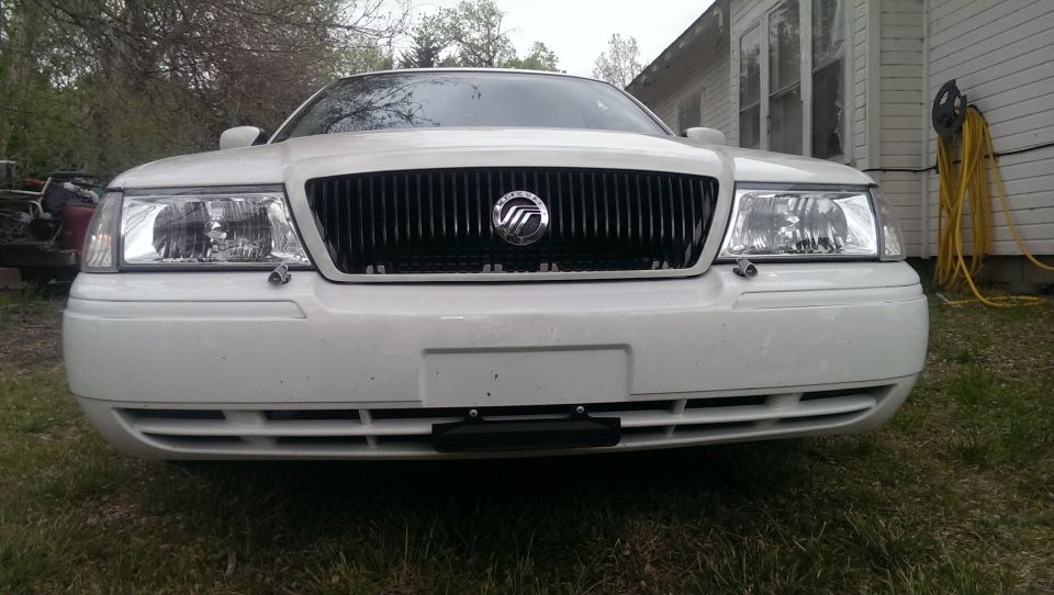 White Mercury Grand Marquis, front view. Vertical grille with Mercury emblem