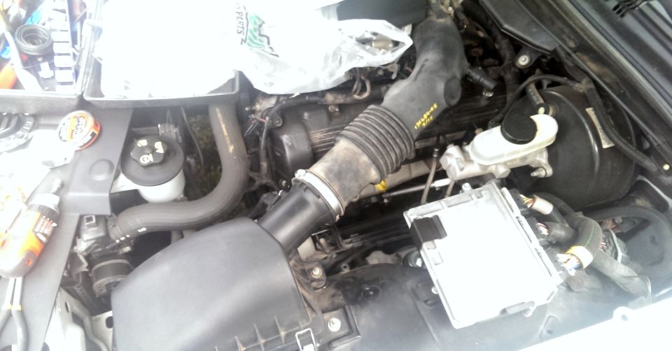 Engine bay with air intake tube, brake booster, and computer module visible