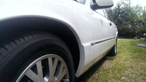 2000 Mercury Grand Marquis - A white sedan is viewed from the side, highlighting its front wheel and chrome body trim.