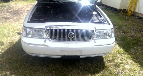 2000 Mercury Grand Marquis - Front view of a white 2000 Mercury Grand Marquis, parked outdoors with the hood open, revealing the engine compartment.