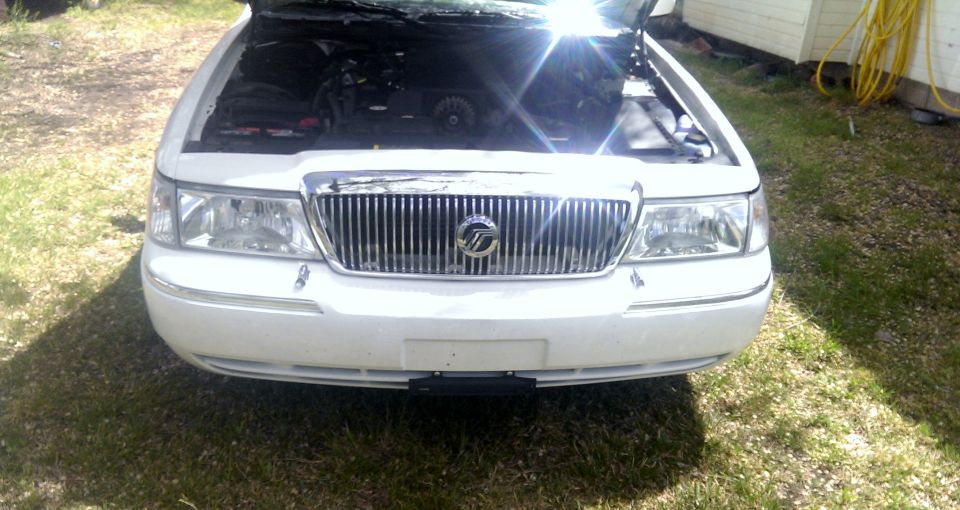 Front view of a white 2000 Mercury Grand Marquis with hood open