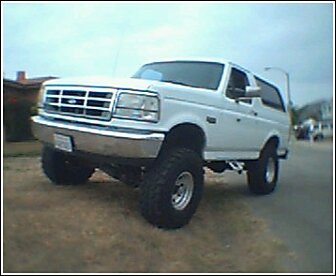 1992 Ford Bronco - A white 1992 Ford Bronco is shown with its suspension lifted and large tires, parked outdoors.