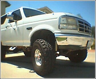 1992 Ford Bronco - This white 1992 Ford Bronco is shown from the front three-quarter view, prominent off-road tires.