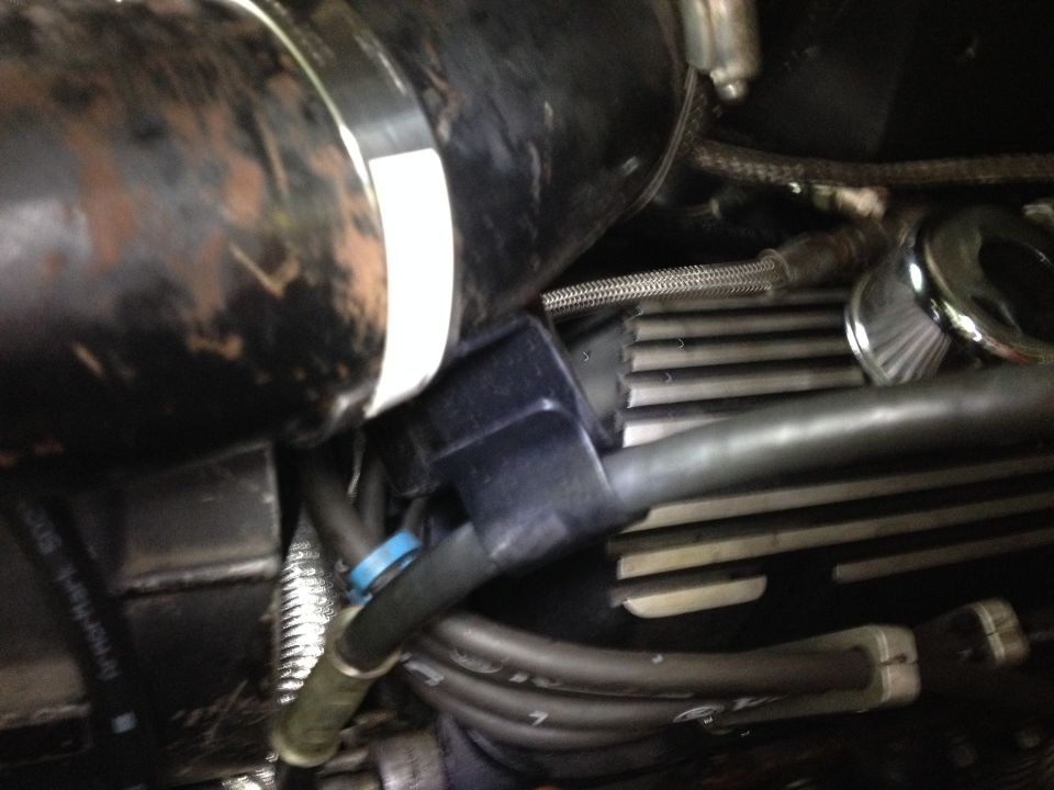 Close-up of engine components including hoses, a black plastic connector, and ribbed metal