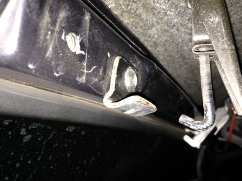 1987 Suzuki Samurai - Detail of a metal bracket and hook mechanism, likely part of a vehicle's interior or undercarriage.
