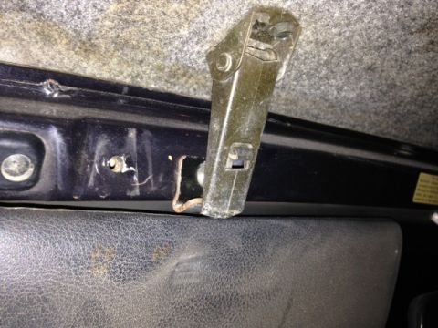 1987 Suzuki Samurai - Close-up view of an interior latch mechanism attached to black trim, with a gray carpeted headliner above.