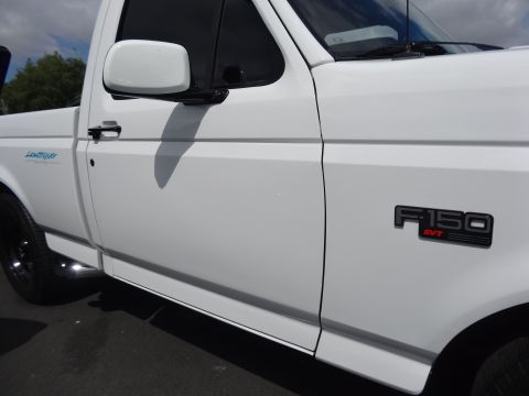 1994 Ford Bronco - Side view of a white 1993 Ford F-150 SVT Lightning pickup truck, highlighting its badges.