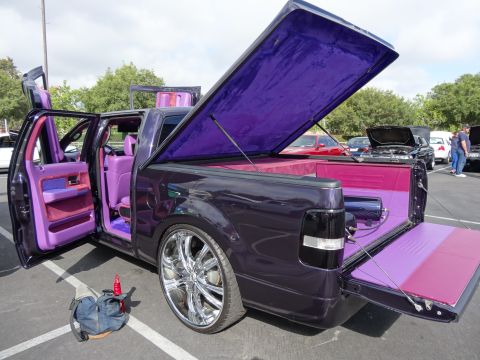 1994 Ford Bronco - Customized pickup truck with extensive purple interior and bed modifications, parked outdoors with other vehicles.