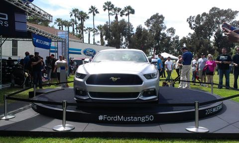 1994 Ford Bronco - A silver Ford Mustang is showcased on a rotating platform at an outdoor event with spectators around.