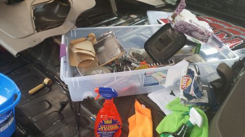 1994 Ford Bronco - Tools, cleaning supplies, and snacks are organized in a storage bin inside a vehicle's cargo area.