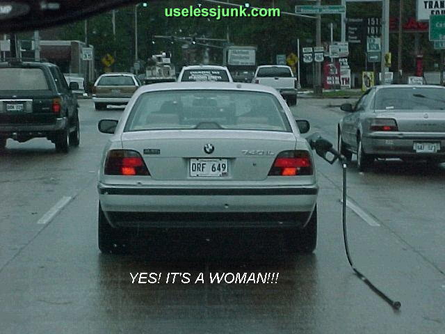 BMW 7 Series sedan with gas pump nozzle in fuel door, other cars on wet road