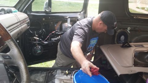 1994 Ford Bronco - Man works on the interior door panel of a vehicle, possibly during soundproofing work.