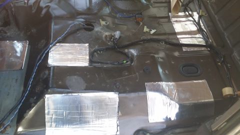 1994 Ford Bronco - Soundproofing material is applied to the floor of a vehicle's interior, with wiring visible.