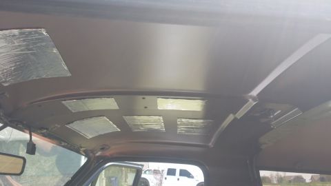 1994 Ford Bronco - Soundproofing material is being applied to the interior ceiling of a vehicle.