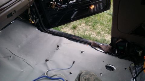 1994 Ford Bronco - The floor of a vehicle is covered in soundproofing material, with the door open and interior panels removed.