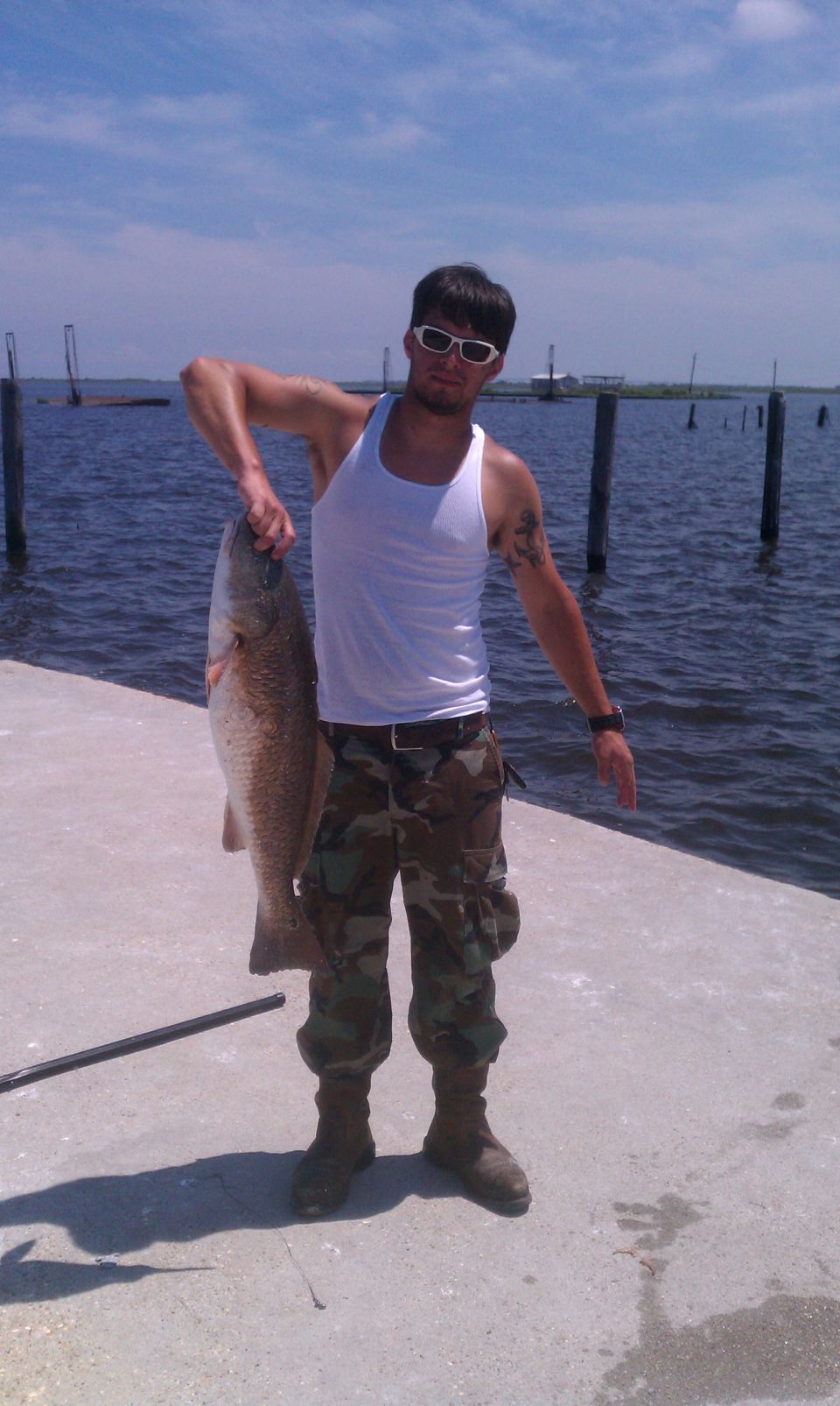Man holding a large red drum fish on a pier