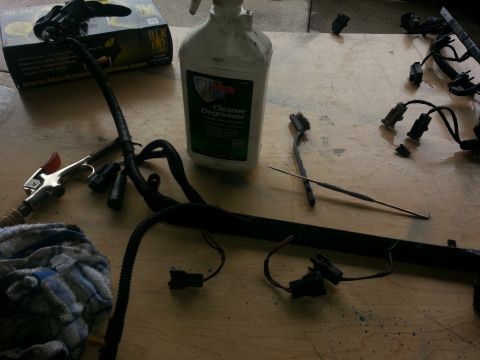 1994 Ford Bronco - Engine wiring harness components and cleaning supplies laid out on a wooden surface.