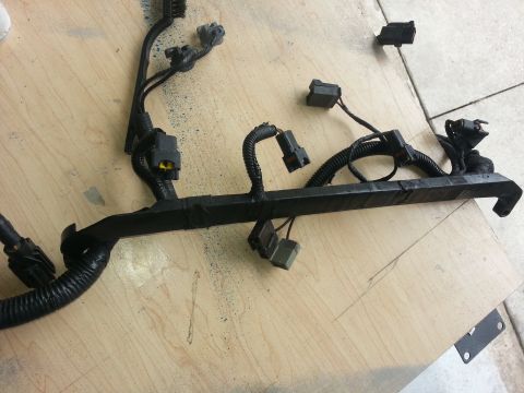 1994 Ford Bronco - A black engine wiring harness with various connectors is laid out on a wooden surface.