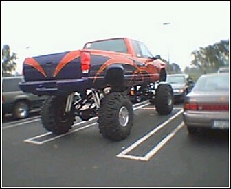 1992 Ford Bronco - This heavily modified pickup truck is parked in a lot, taking up two spaces.