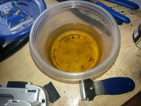 1994 Ford Bronco - Used oil in a plastic container with various tools and parts on a workbench.