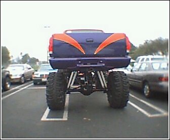 1992 Ford Bronco - A heavily modified pickup truck with custom paint and large tires is parked in a lot.