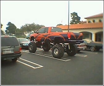 1992 Ford Bronco - A heavily modified pickup truck with oversized tires and custom graphics is parked in a lot.