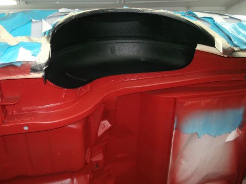 1967 Ford Mustang - Close-up of the interior of a 1967 Ford Mustang, showing red painted metal and a black wheel well, likely during restoration.
