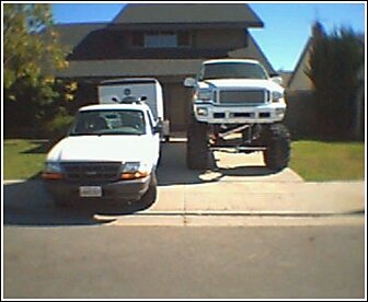 1992 Ford Bronco - Two trucks are parked in a driveway, one is significantly lifted.