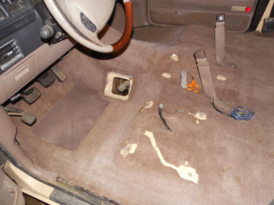 Ford truck interior with new tan carpet cut around shifter hole and seat belt anchors
