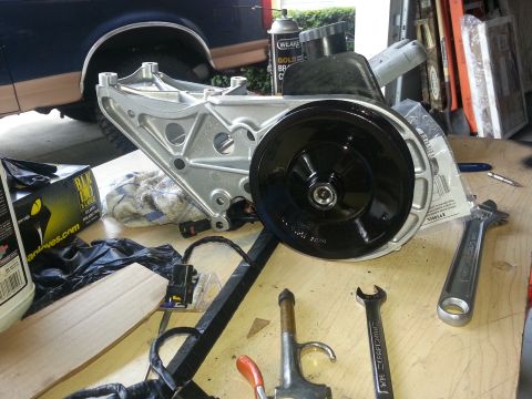 1994 Ford Bronco - A power steering pump assembly is laid out on a workbench with tools, with a portion of a blue truck visible in the background.