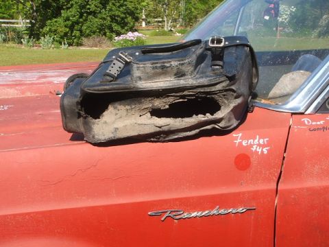 1998 Honda Shadow VT750C - A damaged black leather motorcycle saddlebag rests on the fender of a red vehicle, with handwritten text visible on the fender.