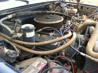 1995 Ford Bronco - The engine bay of a vehicle, showing the V8 engine, air cleaner, and various hoses and wires.