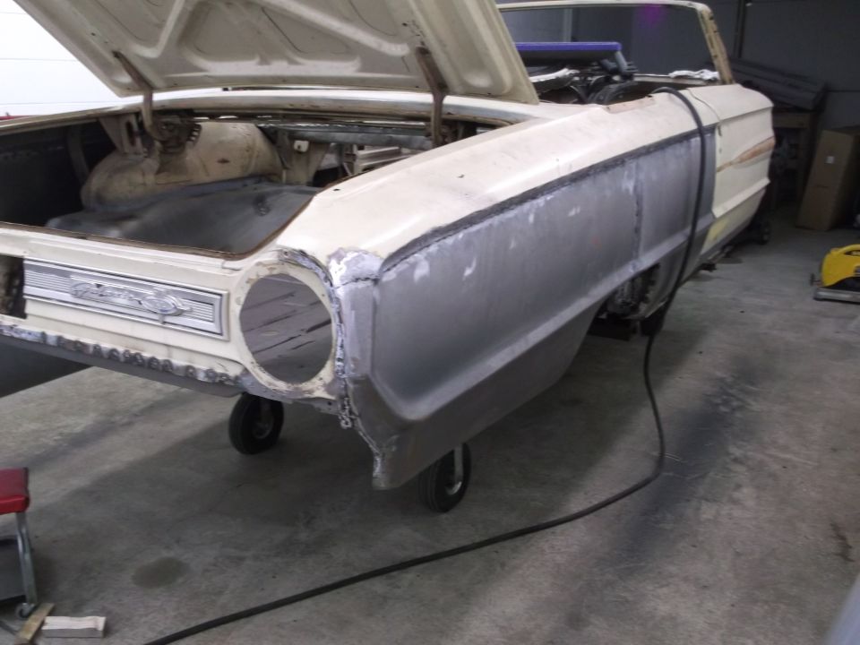 1964 Ford Galaxie body in repair, primer gray fender, open trunk, missing headlight