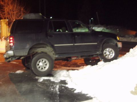 1998 Ford Expedition - A dark blue 1998 Ford Expedition with a lifted suspension navigates a snowy incline at night.