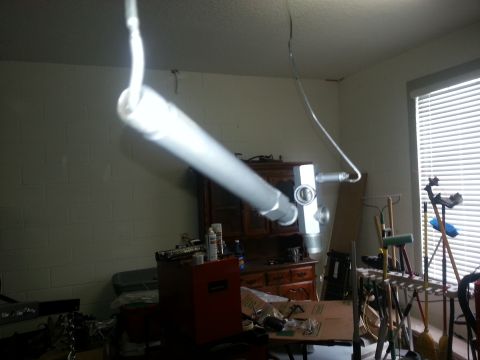 1994 Ford Bronco - A silver exhaust pipe and catalytic converter are suspended from the ceiling in a room with blinds and furniture.