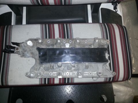 1994 Ford Bronco - An engine intake manifold is shown resting on striped upholstery, likely in a workshop or garage setting.