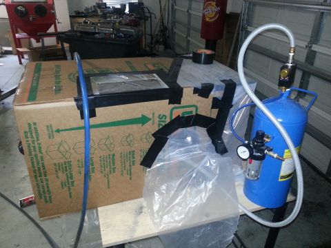 1994 Ford Bronco - A setup involving a large cardboard box, air compressor, and sandblaster is shown in a garage setting.
