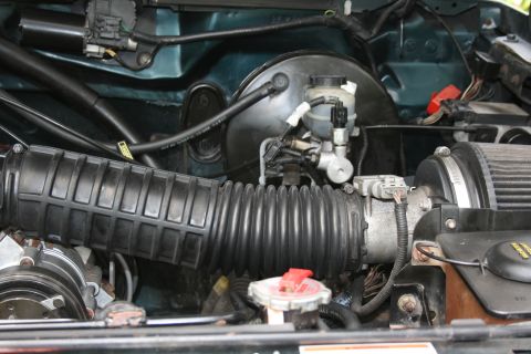 1994 Ford Bronco - Close-up view of engine bay components, including the air intake and brake system, in a teal vehicle.