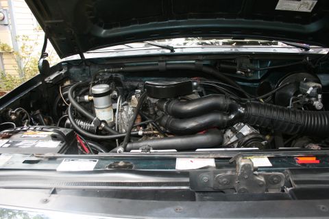 1994 Ford Bronco - The engine compartment of a vehicle is shown with the hood open, revealing various mechanical parts and electrical components.