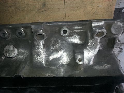 1994 Ford Bronco - This is a close-up view of a cast metal engine block part, showing bolt holes and casting marks.