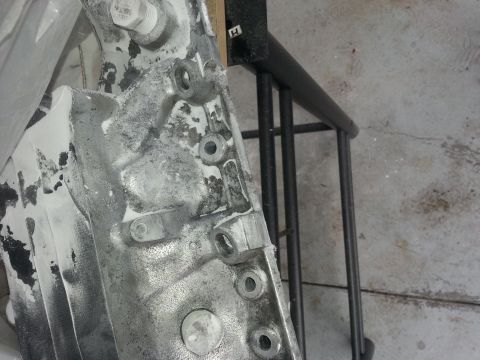 1994 Ford Bronco - A close-up view of a cast metal engine component, likely part of a transmission or engine block, showing various bolt holes and mounting po…